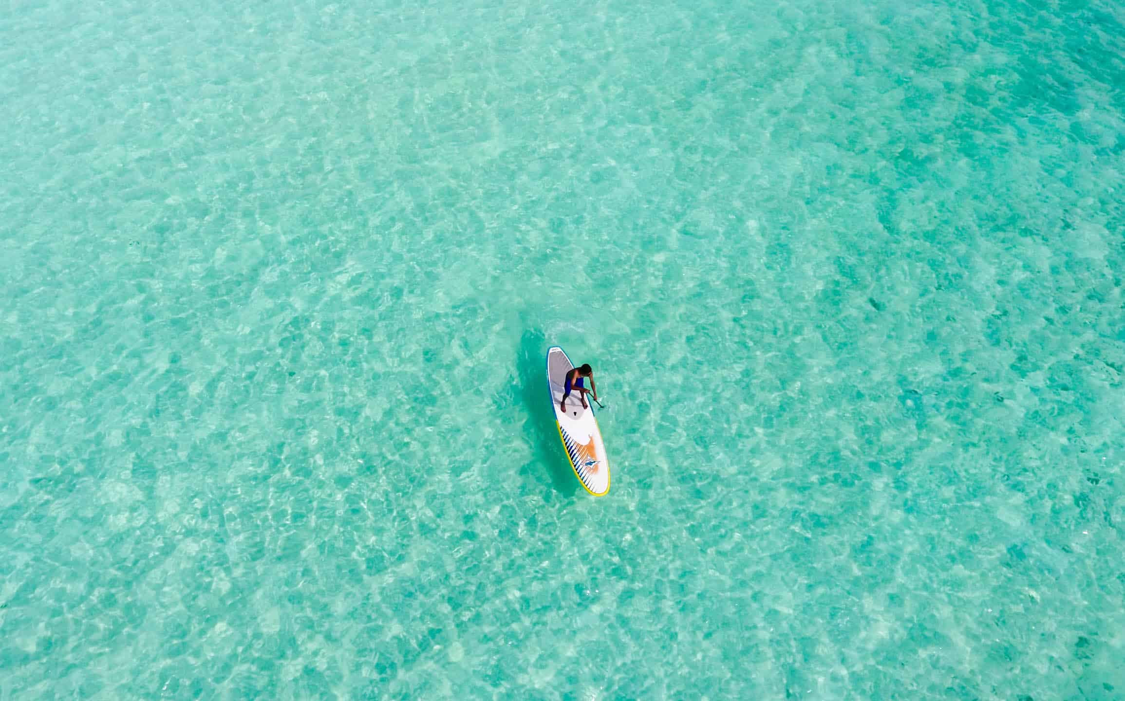 Guadeloupe, un homme sur un stand up paddle dans l'eau turquoise